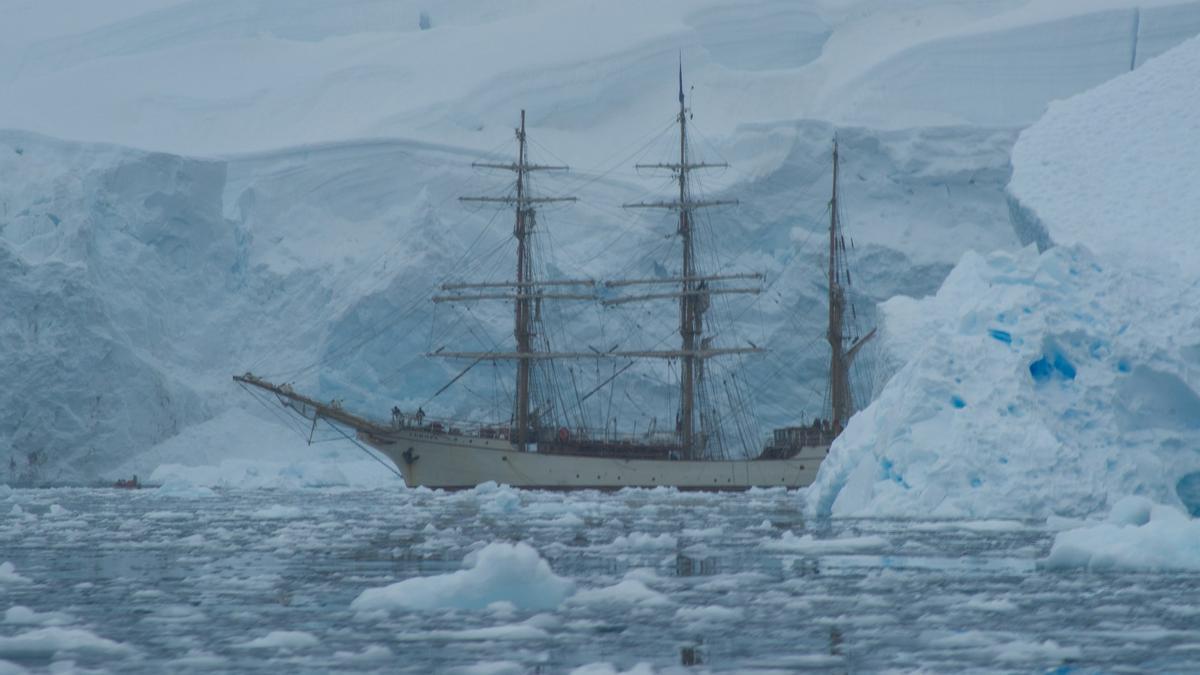 Un barco navega junto a la costa antártica.