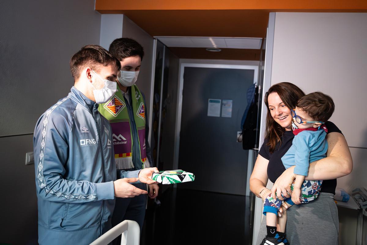 Peña y Ernesto le dan un regalo a un niño.
