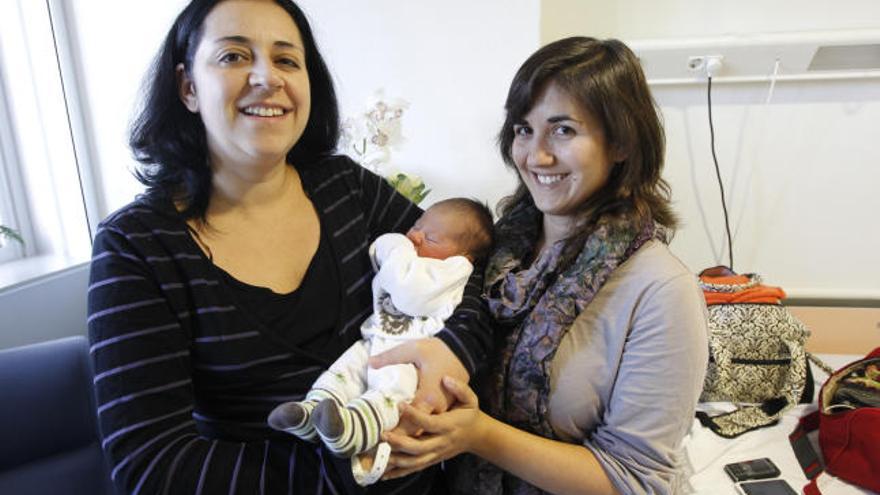 Marta Obrador e Isabel Castelló (a la derecha), de 31 y 30 años, sostienen a su hija Alejandra en el hospital Clínic de Valencia, ayer.