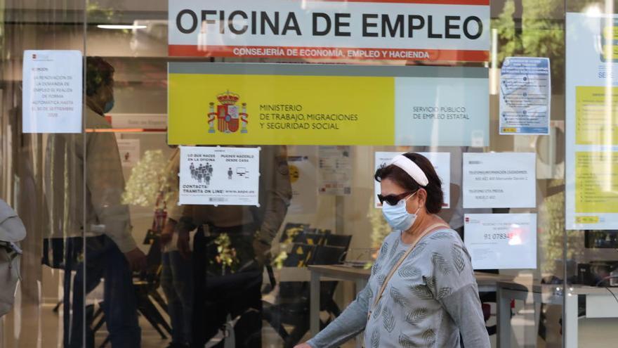 Una mujer con mascarilla pasa por una oficina de empleo de Madrid.