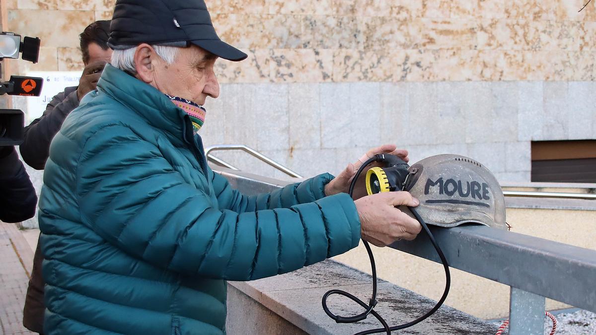 El padre de uno de los mineros fallecidos coloca el casco de su hija en las puertas del juzgado de León.