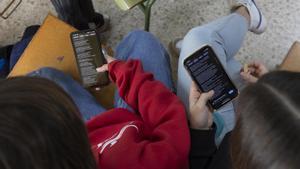 Dos adolescentes consultan su teléfono móvil en un instituto catalán, este curso.