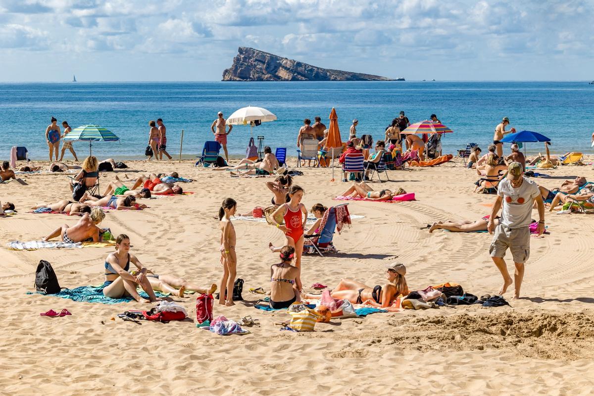 Los primeros turistas que ya han desembarcado en Benidorm, aprovechando esta mañana de las altas temperaturas para disfrutar de la playa.