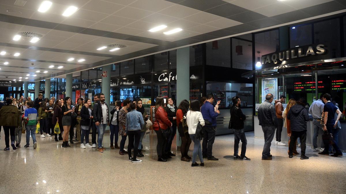 Personas hacen cola en un cine para adquirir entradas.