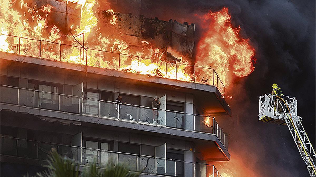 Un bombero se acerca a rescatar a dos residentes del edificio en llamas en Campanar, Valencia.