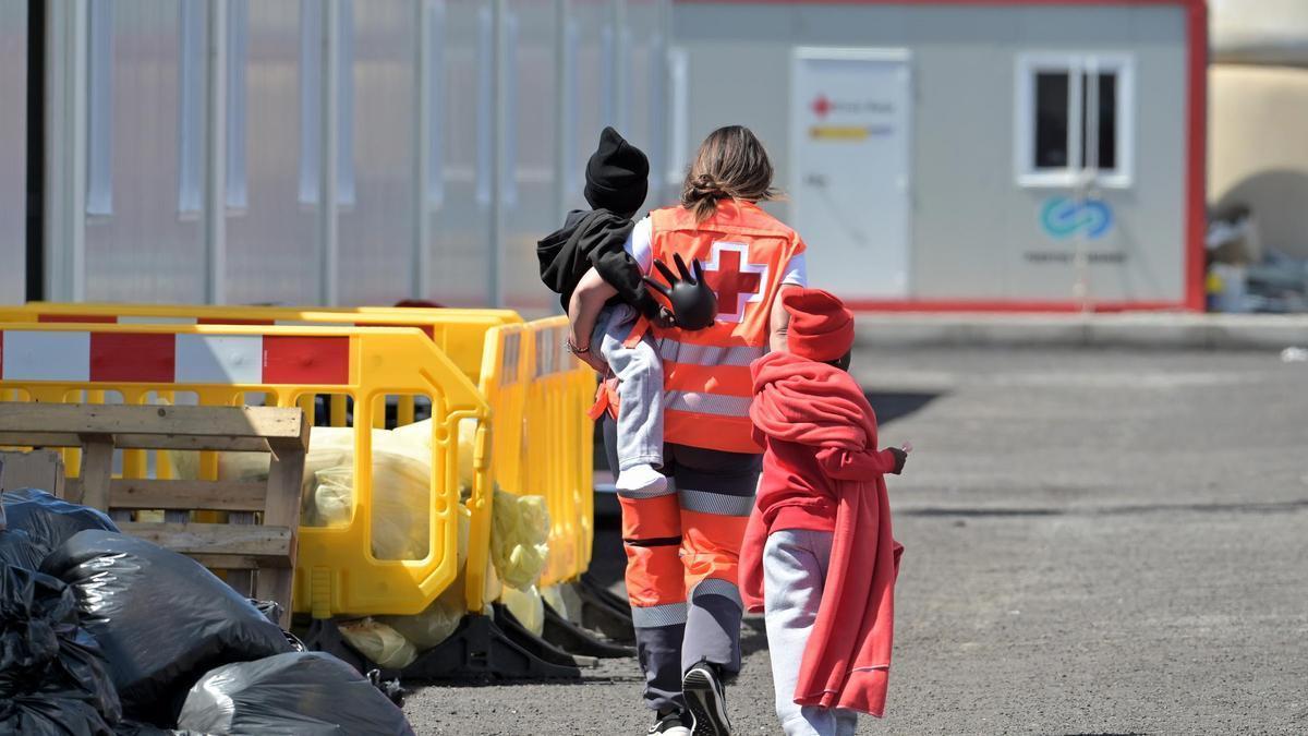 Una trabajadora de Cruz Roja atiende a dos menores que llegaron en cayuco a El Hierro.