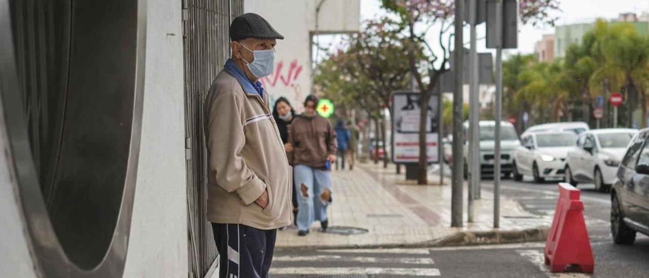 Un jubilado canario espera sobre la acera en una calle de Tenerife.   | | CARSTEN W. LAURITSEN