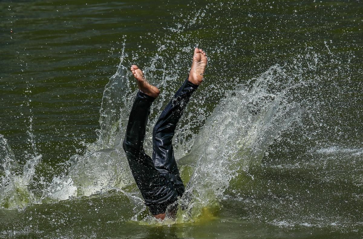 Un hombre indio salta a un estanque para refrescarse durante la ola de calor en Bombay, India.