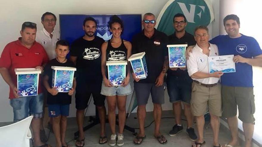 Responsables de los clubes de buceo de Xàbia con los contenedores de recogida selectiva de plomo.