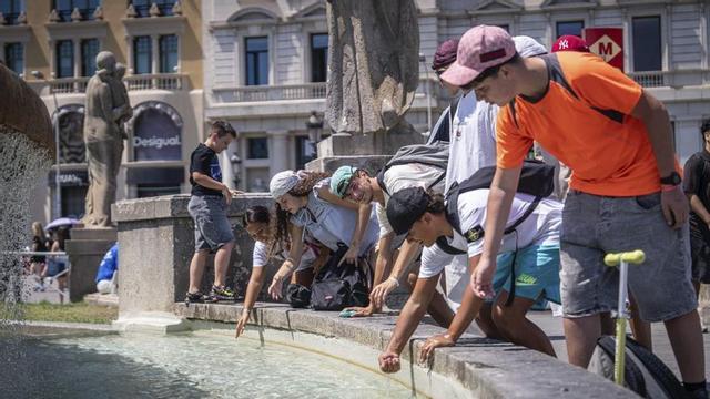 Un grup de joves es refresquen al centre de Barcelona fa uns dies per les altes temperatures. | MANU MITRU