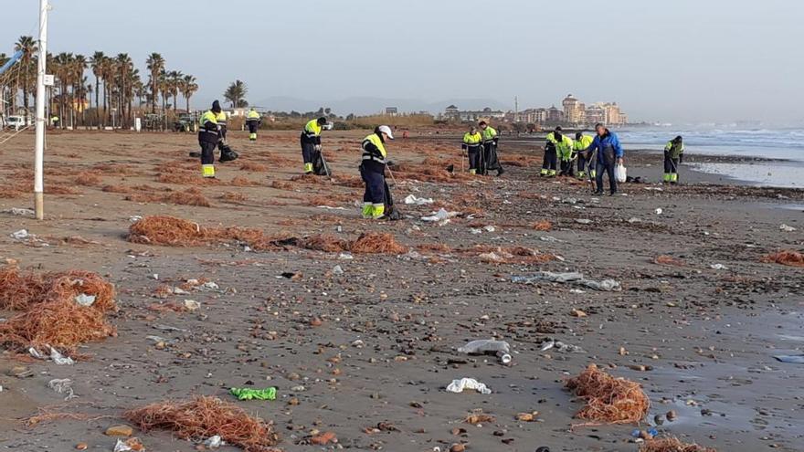 Operarios limpiando la playa de la Patacona con los restos del temporal.