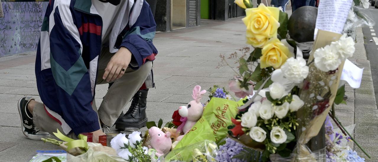 Un joven se arrodilla ante el altar colocado en la acera donde fue golpeado Samuel.