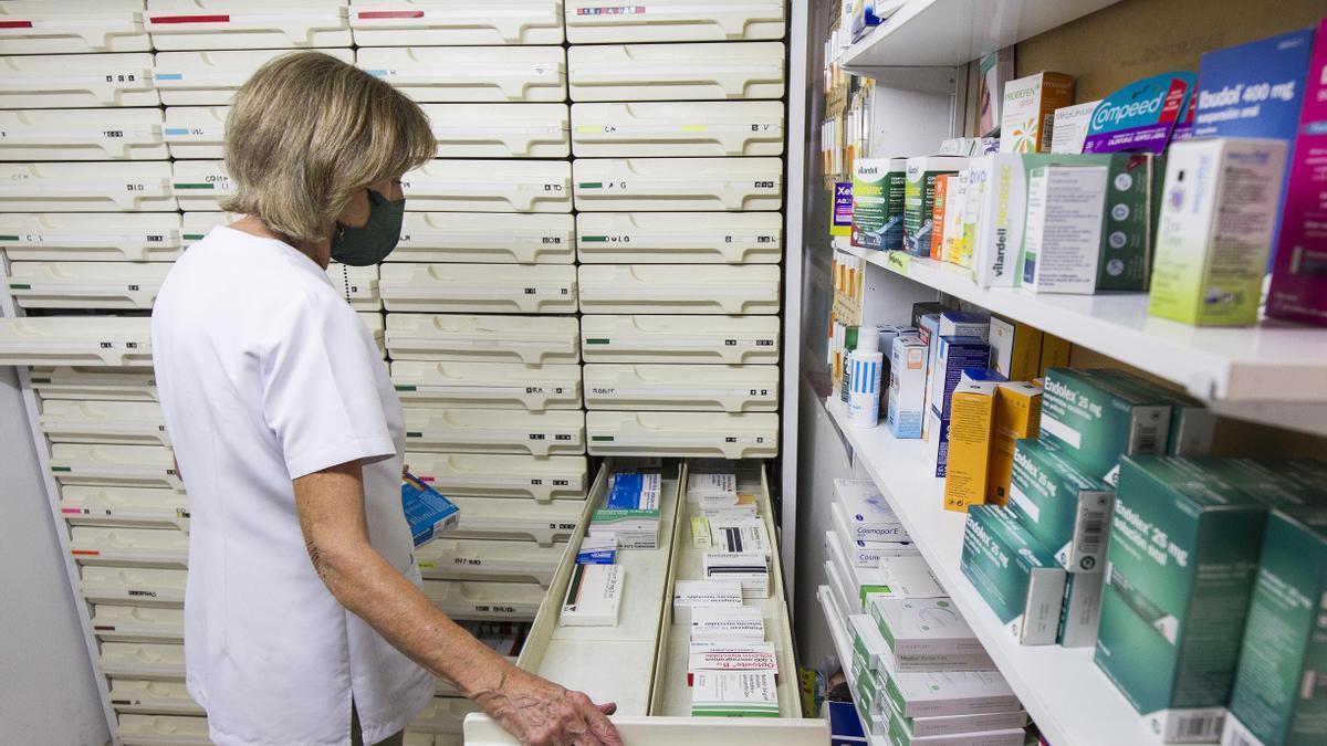 Una farmacéutica busca un medicamento en el interior de su establecimiento.