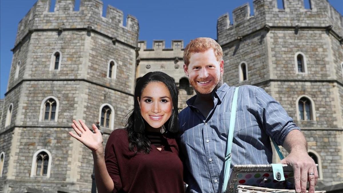 Una pareja con caretas de Meghan y Enrique, ante el castillo de Windsor.