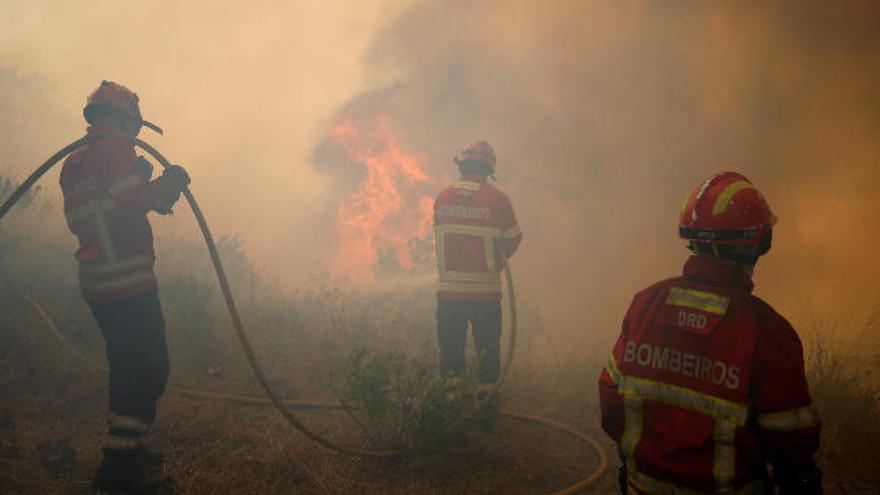 Tres bomberos luchan, en la localidad de Capelo, contra el incendio que dejó más de sesenta fallecidos.