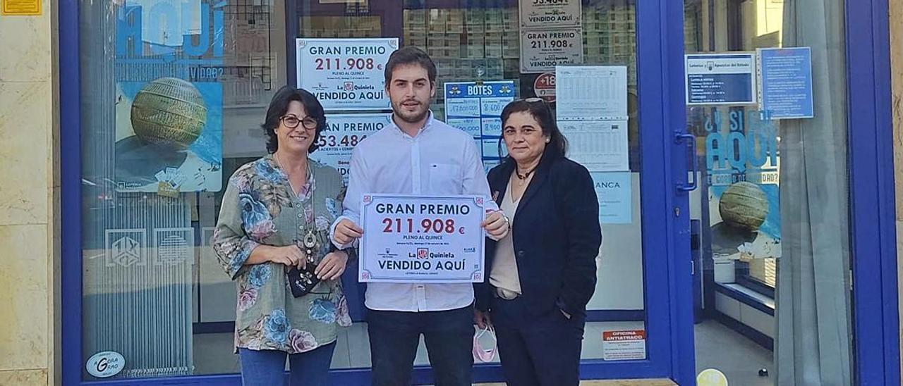 Maite Canal, encargada de la administración, Sergio Palacio, hijo y trabajador, y Anna Rodríguez, trabajadora de la administración, posan con el cartel del premio, ayer, en Grado. | B. G.