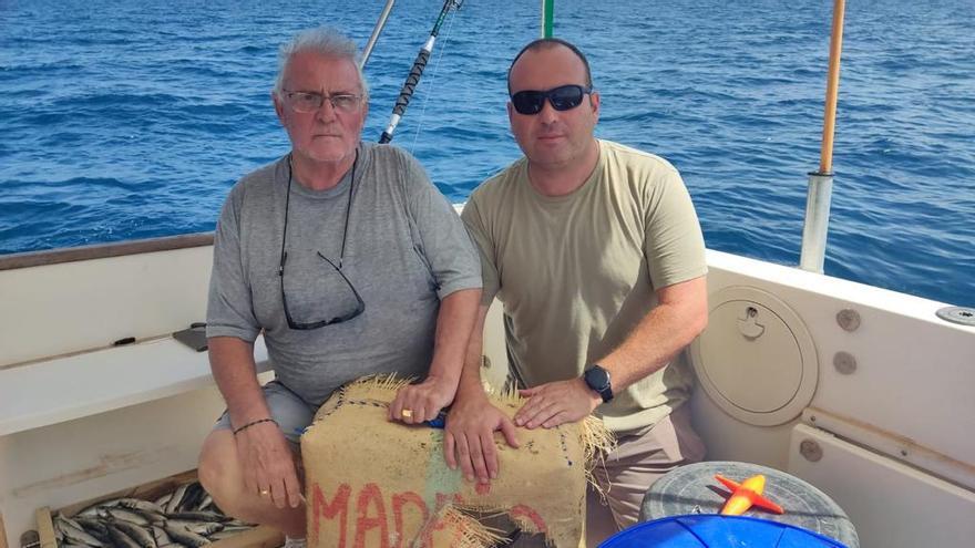 Los dos pescadores con el fardo de hachís encontrado en el mar.