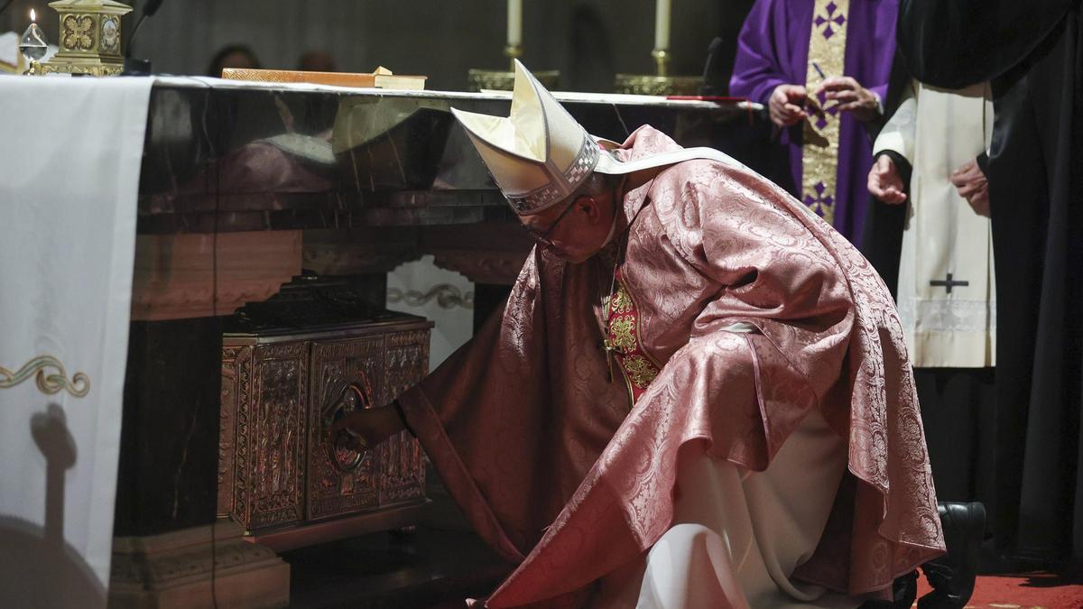 El Arzobispo se agacha bajo el altar mayor de la Catedral para cerrar la arqueta con las reliquias de los cinco mártires.