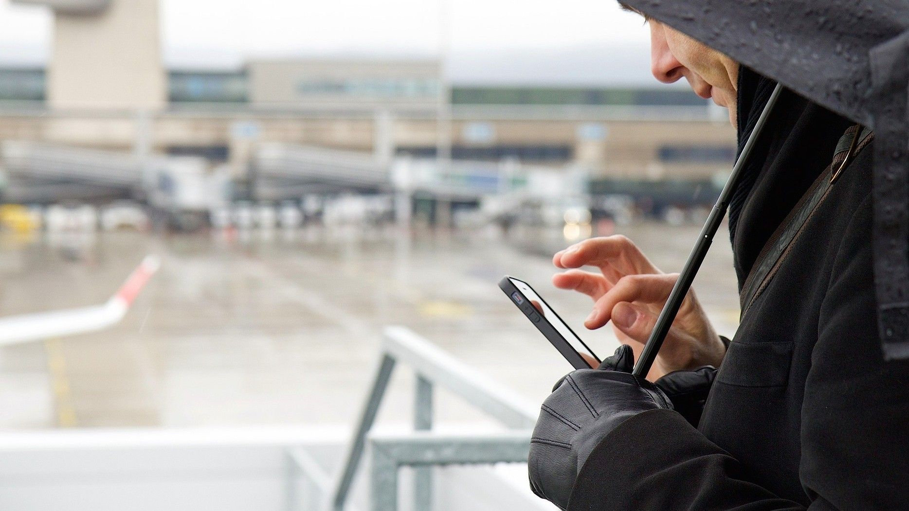 Un hombre manipula su teléfono móvil cerca de las pistas de aterrizaje de un aeropuerto