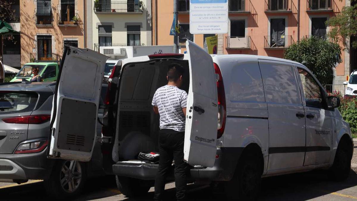 Un transportista descarregant mercaderies mentre està aparcat en una zona de càrrega i descàrrega de la plaça de Catalunya de Girona