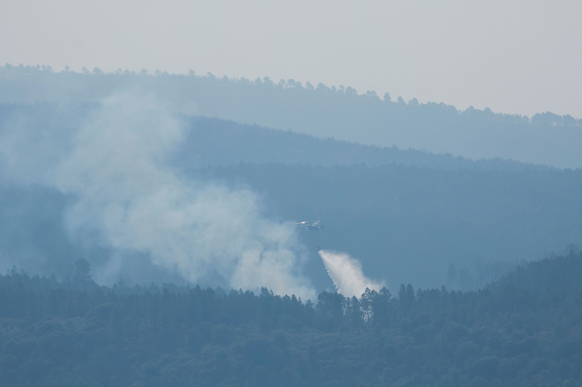 A fire fighting helicopter works to contain a wildfire during the second heatwave of the year in Serranilla de Llano