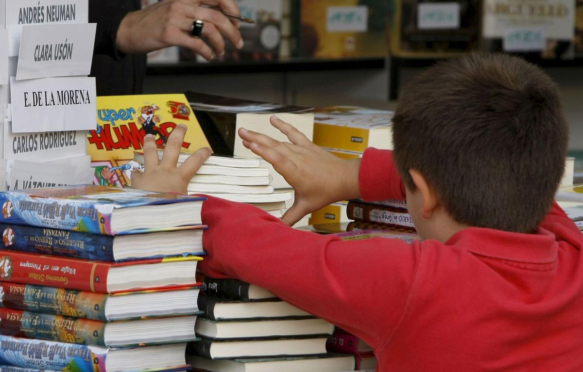 Un niño ante libros infantiles en una de las casetas de la Feria del Libro de Madrid.