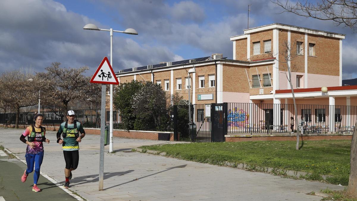 Dos deportistas pasan delante del colegio Alfonso Churruca, en la barriada de Las Palmeras.