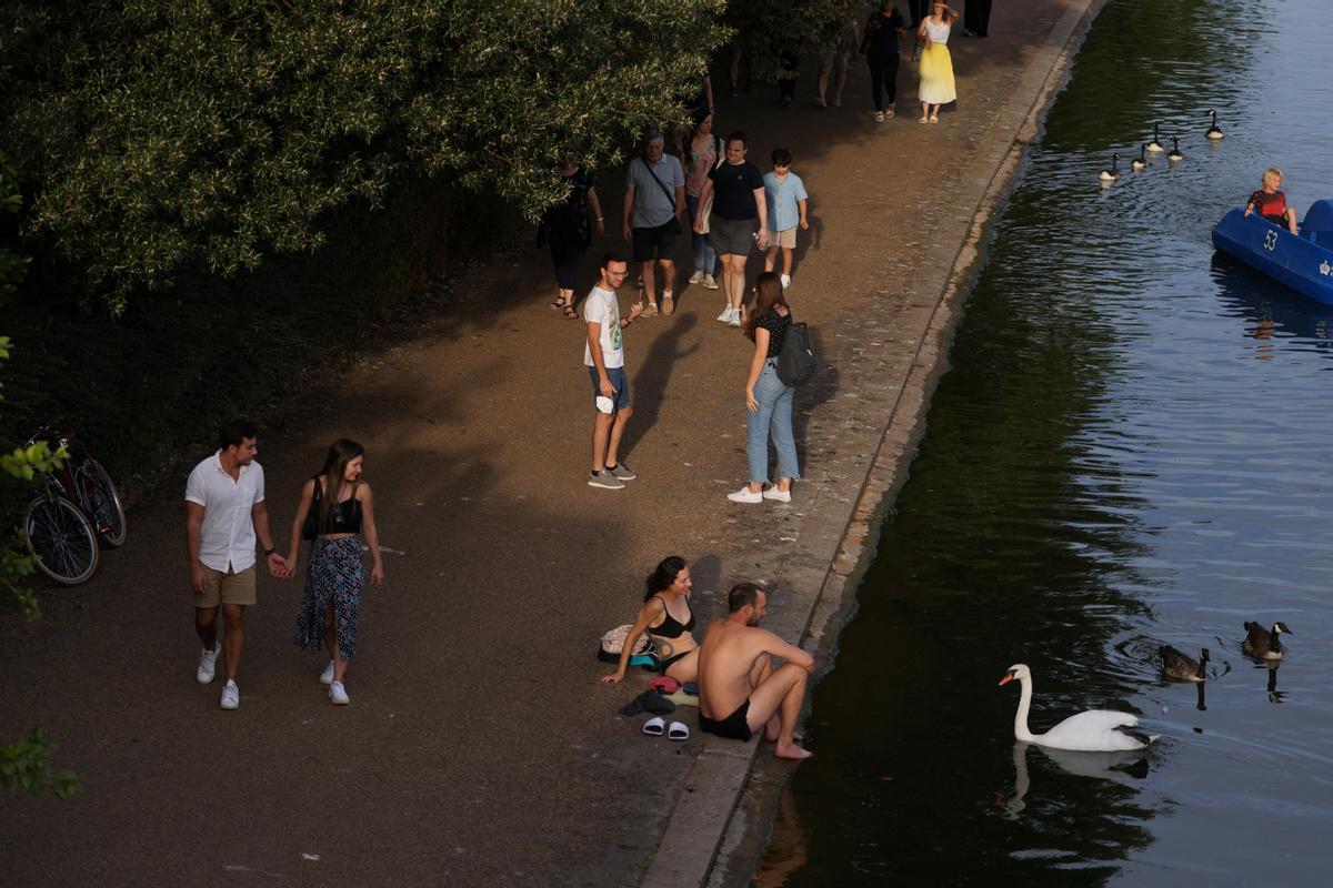 Un grupo de gente se refresca junto al lago The Serpentine, en Hyde Park, en Londres, para combatir las altas temperaturas que se registran en la ciudad