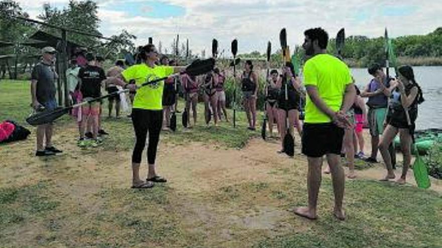 A derecha e izquierda, dos monitores instruyen a los estudiantes sobre cómo utilizar los remos y mantener el equilibrio en los kayak; en el centro, se preparan para entrar al río.