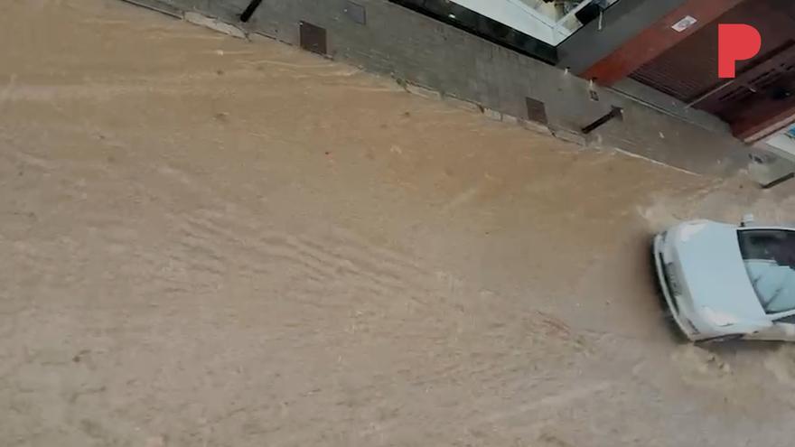 El agua baja en forma de riada por la calle Miquel Servet de Badalona, tras las intensas lluvias de este martes por la tarde