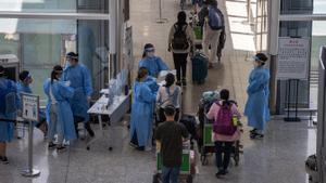 Personal sanitario en el aeropuerto internacional de Hong Kong conduce a los positivos en coronavirus, con código rojo, a un hotel donde cumplirán una cuarentena.
