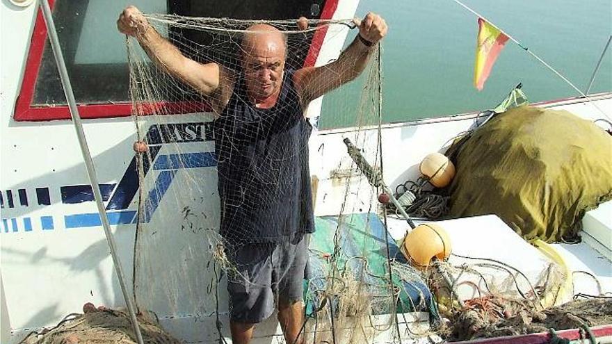 Un pescador ayer en el puerto de Guardamar mostrando una de las redes destrozadas por los ladrones de pescado.