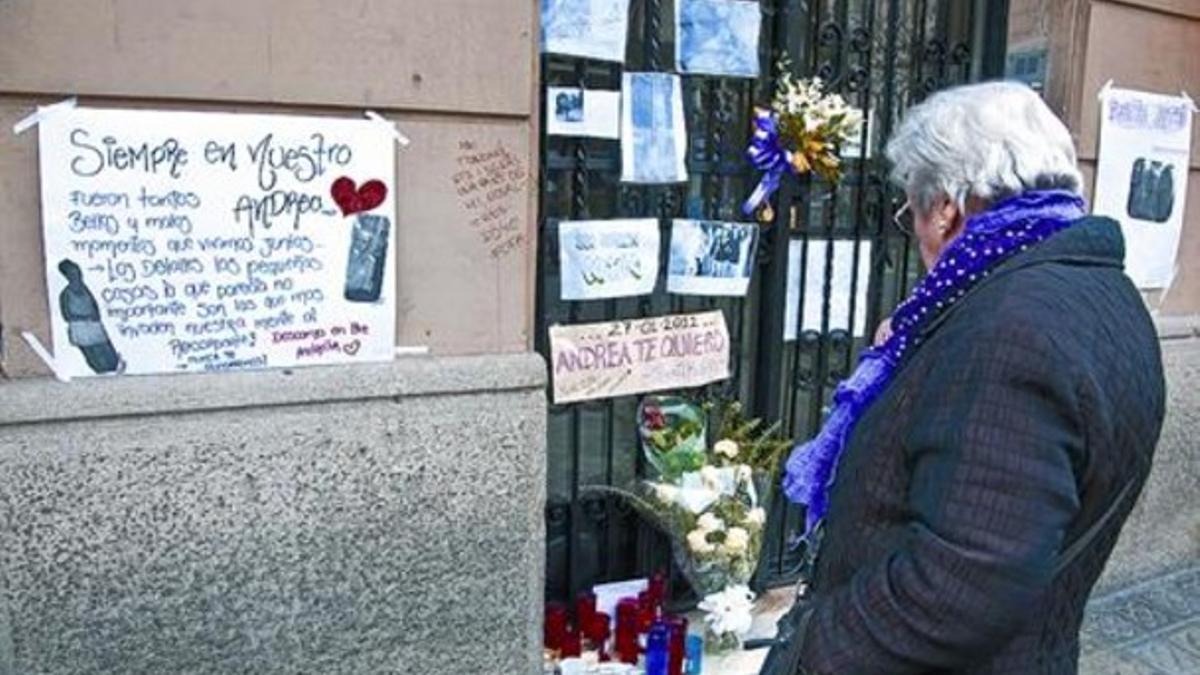 Una mujer contempla los mensajes y las velas en el portal de las víctimas del triple crimen, ayer.