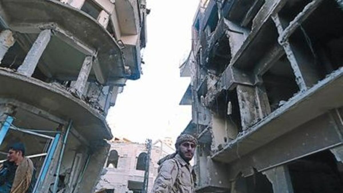 Un combatiente del Ejército Libre Sirio camina entre edificios bombardeados en un barrio de Damasco.