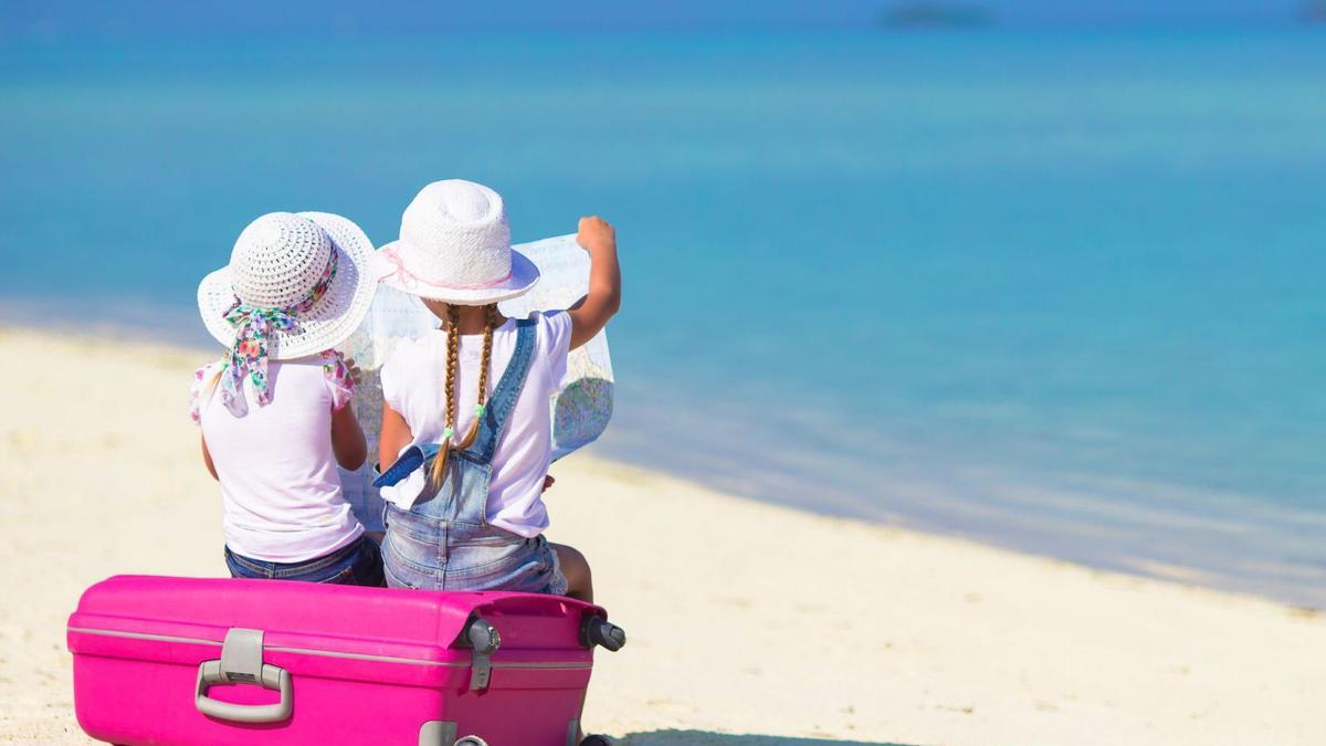Dos niñas miran un mapa sentadas sobre una maleta. |  // FDV