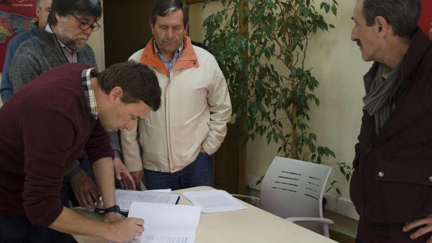 Julio Antuña firma la petición con el Alcalde de Illas, Alberto Tirador, y Fernando Díaz Rañón detrás.