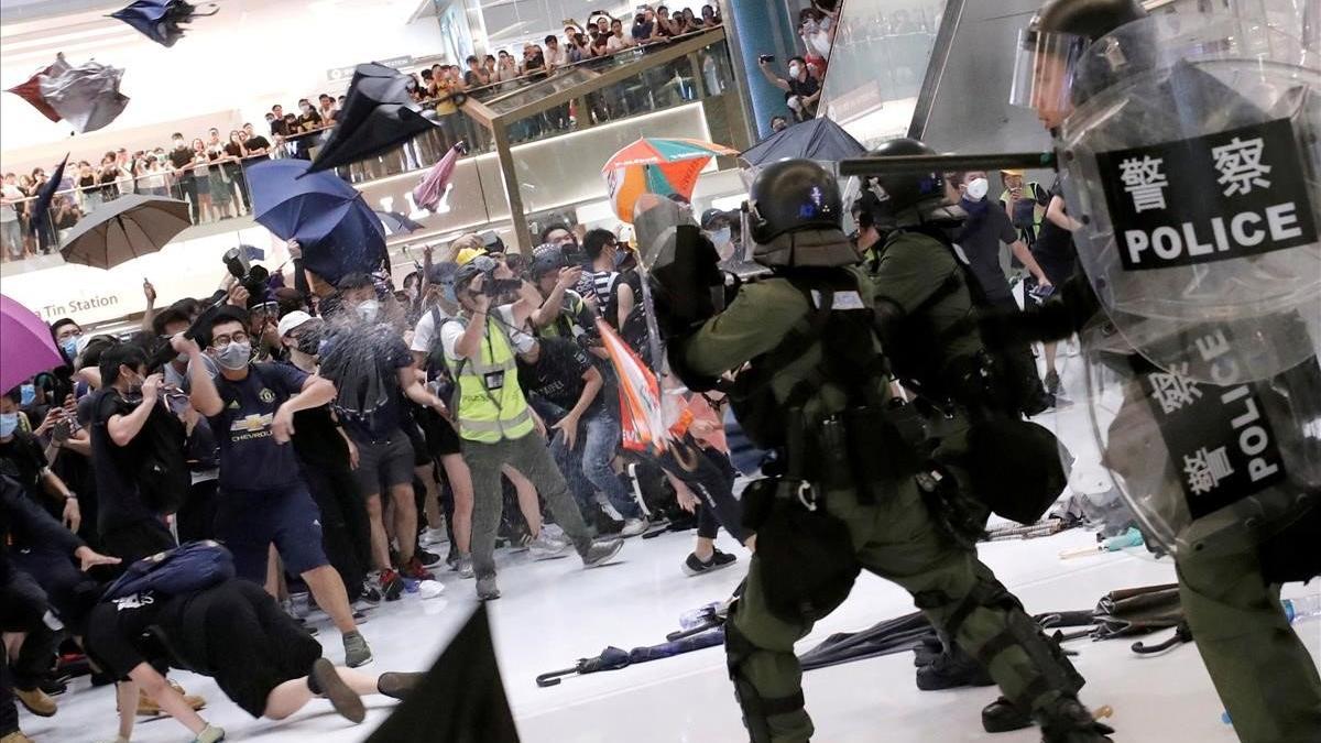 Manifestantes lanzan paraguas contra policías antidisturbios en un centro comercial de Hong Kong.