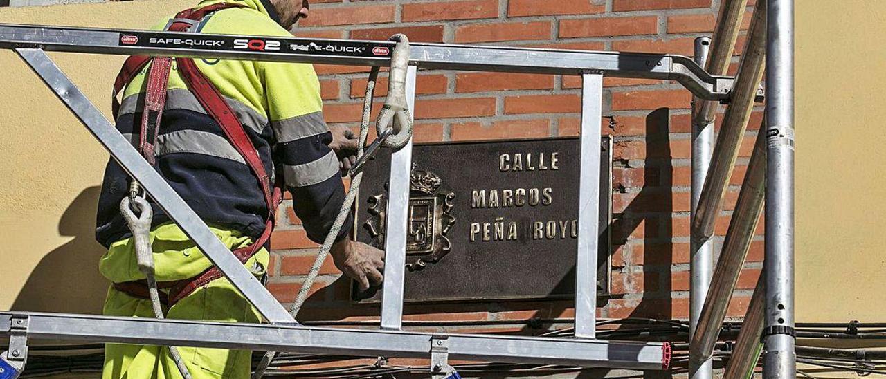 Un operario, reponiendo la placa de la calle Marcos Peña Royo.