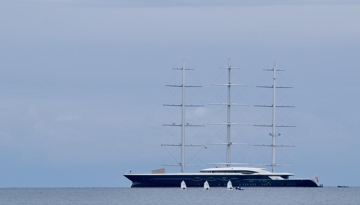 Tres optimist pasan por delante del Black Pearl, en la bahía de Palma