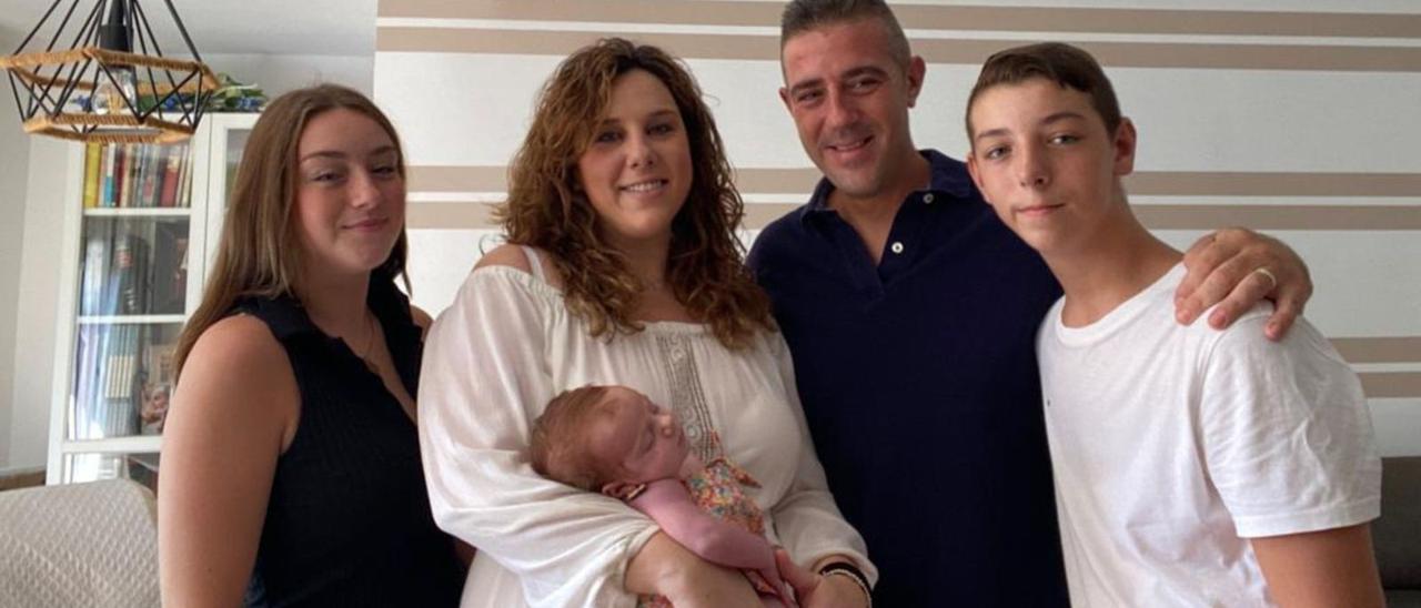 Bea Solanes, con la pequeña Pau en brazos, e Ivan Canet, padre de la pequeña, con los otros dos hijos de este, en su casa de Tavernes. | LEVANTE-EMV