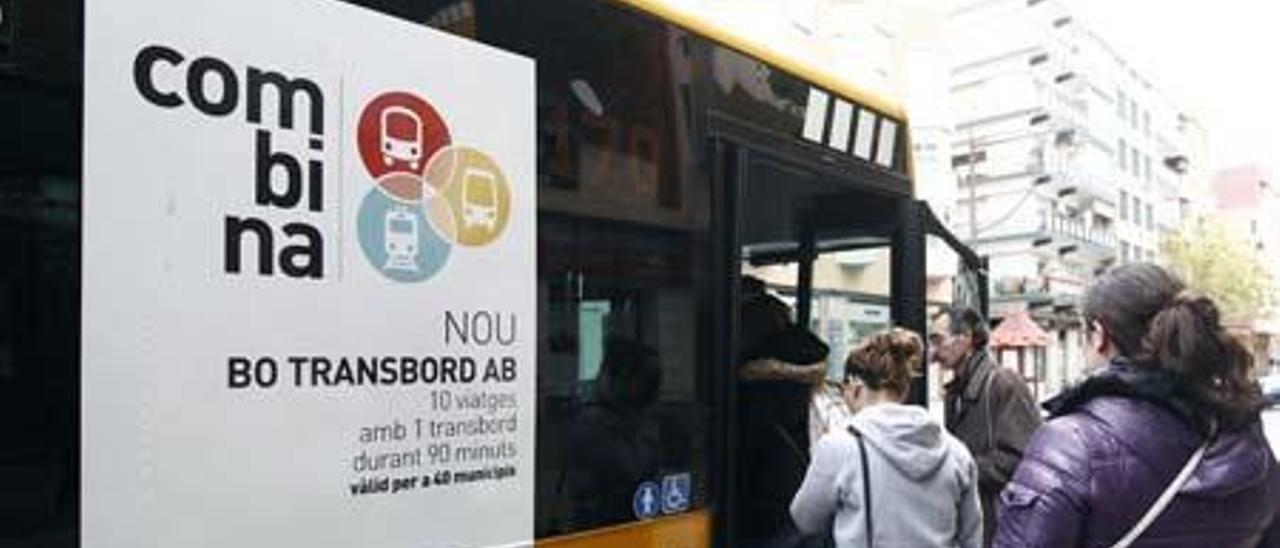 Usuarios del metrobús de una parada de Xirivella pasan ante el cartel que anuncia el nuevo bono.