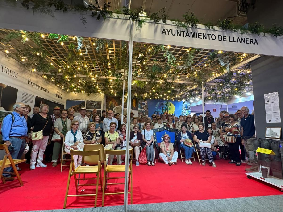 Foto de familia de jubilados y pensionistas de Llanera, en el stand, con la alcaldesa, sentada en el suelo, en el centro.