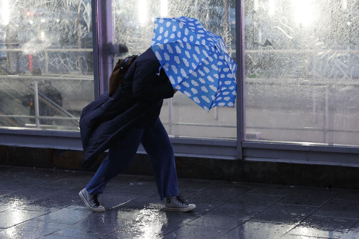 Una persona se protege de la lluvia que cae este lunes en la ciudad de Madrid. EFE/ Mariscal