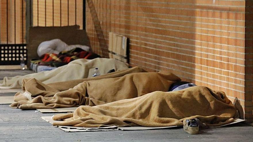 Varias personas duermen en un portal de València.