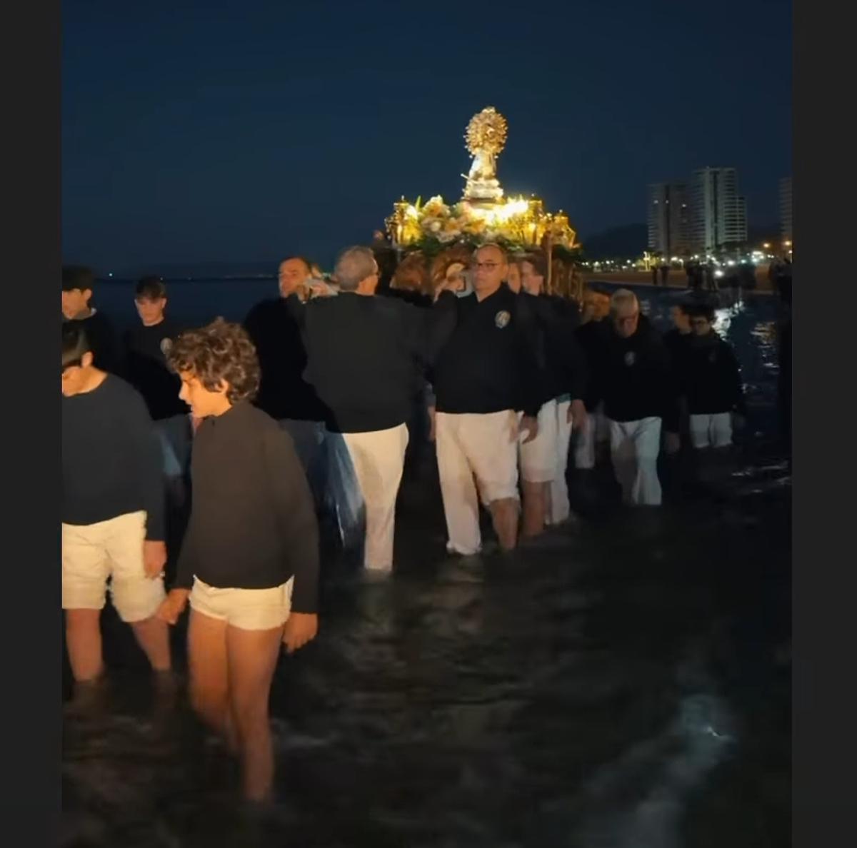 La patrona, a hombros por la orilla del mar, en la Aurora.