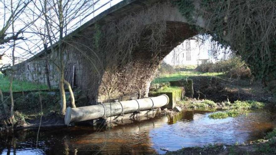 Puente Noalla, sobre el río Barbaña, y, pegado al arco, la tubería de residuos industriales.  // Iñaki Osorio