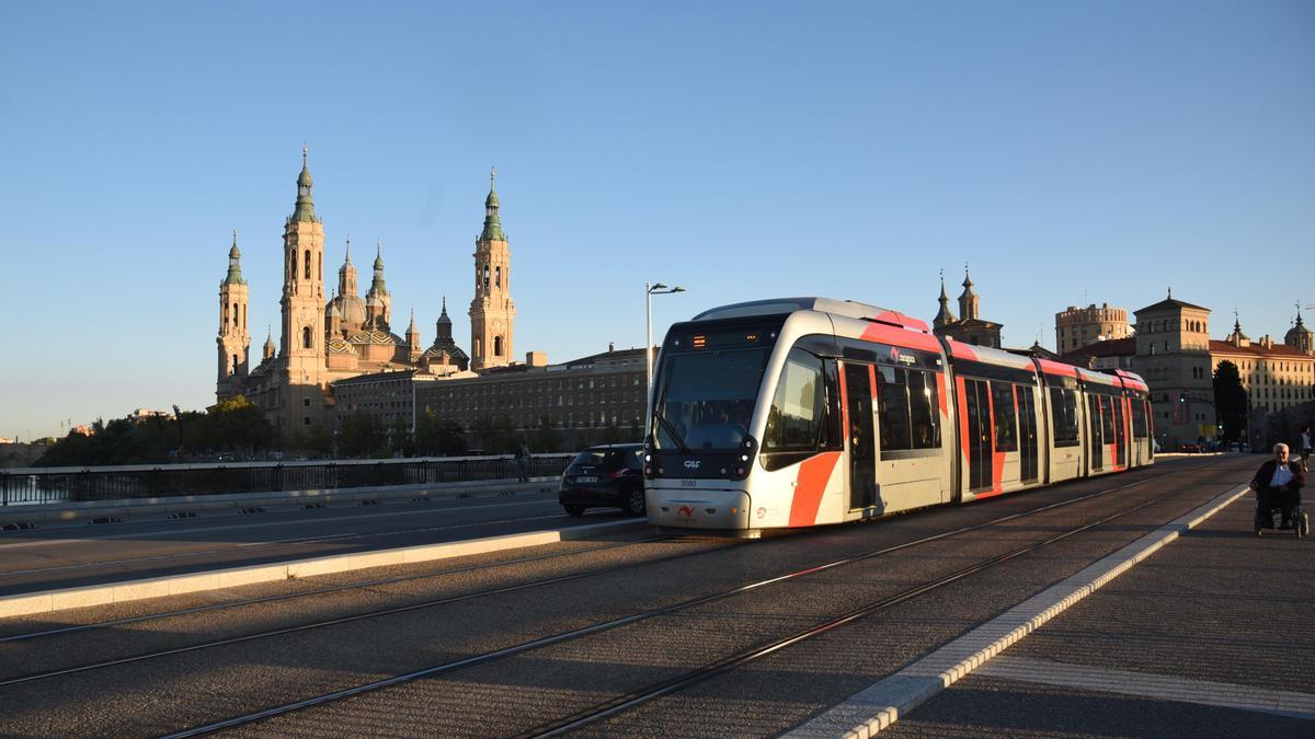 Un convoy del tranvía a su paso por el puente Santiago, con la basílica del Pilar al fondo.