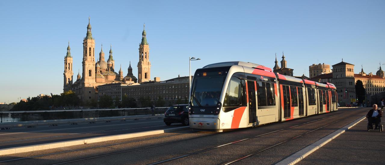 Un convoy del tranvía a su paso por el puente Santiago, con la basílica del Pilar al fondo.