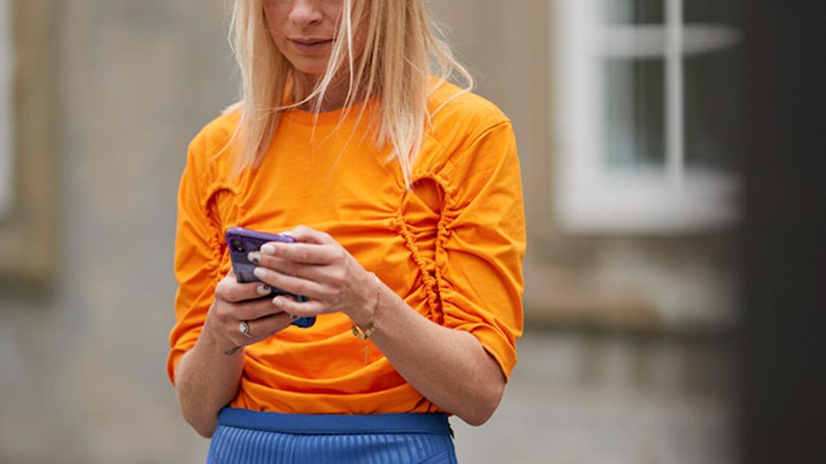 Chica mirando el móvil en el streetstyle de Copenague Primavera Verano 2020