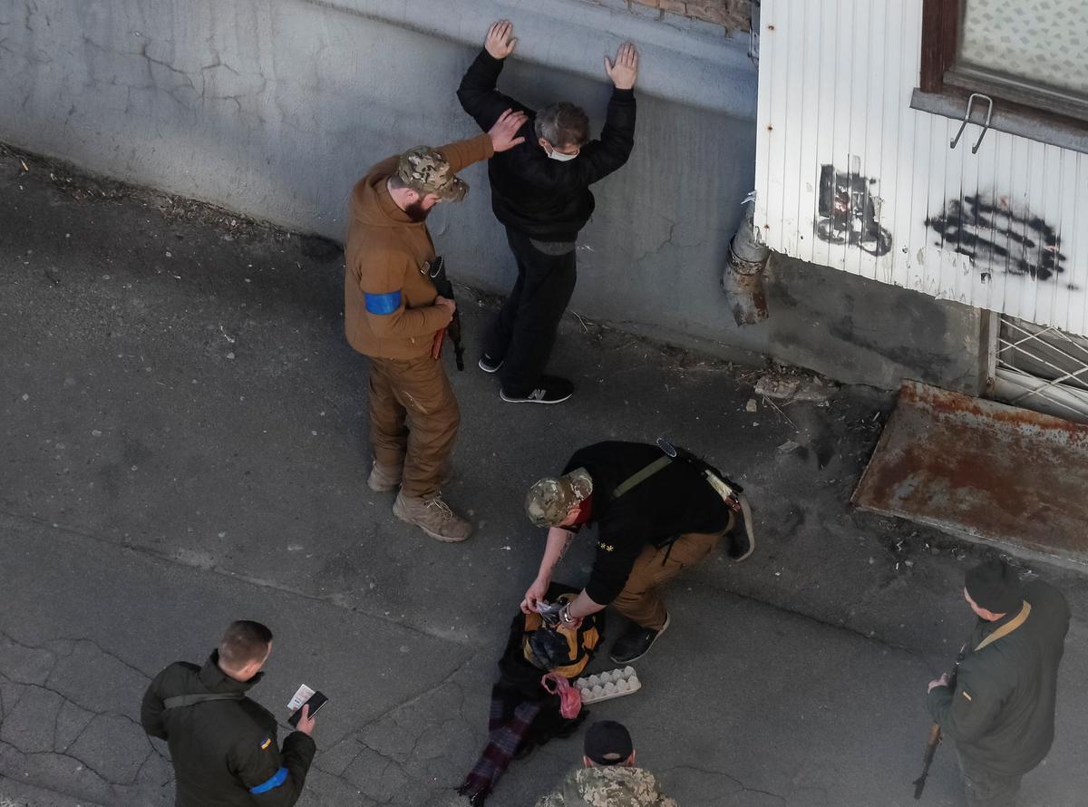 Miembros de las Fuerzas de Defensa Territorial de Ucrania controlan a un hombre mientras patrullan durante un largo toque de queda en Kiev, Ucrania.